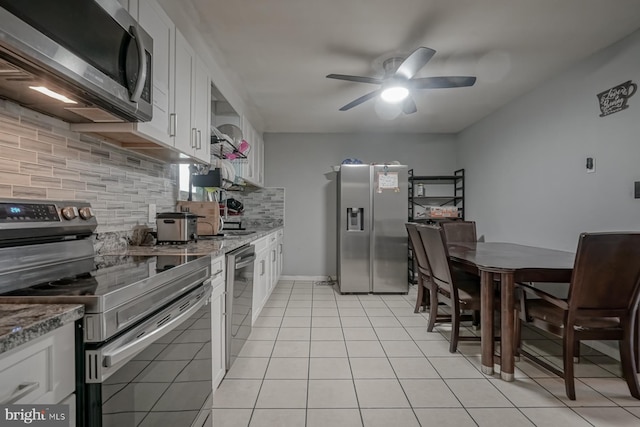 kitchen featuring light tile patterned floors, stone countertops, stainless steel appliances, white cabinetry, and backsplash