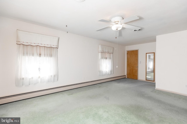 empty room with carpet, a baseboard radiator, a ceiling fan, and a healthy amount of sunlight