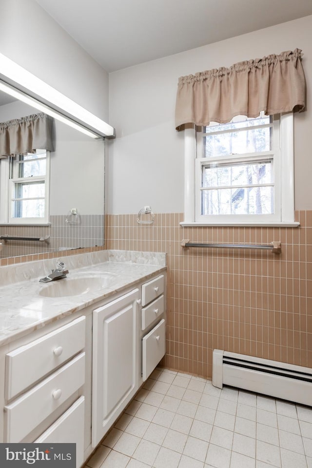 bathroom with wainscoting, a baseboard radiator, tile patterned floors, vanity, and tile walls