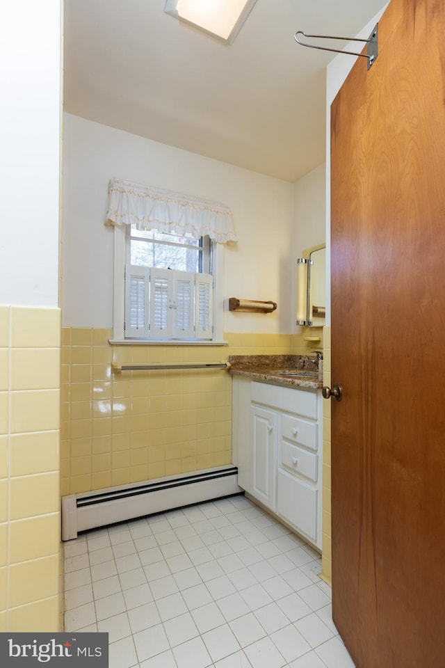 bathroom with a baseboard radiator, tile patterned flooring, a wainscoted wall, vanity, and tile walls