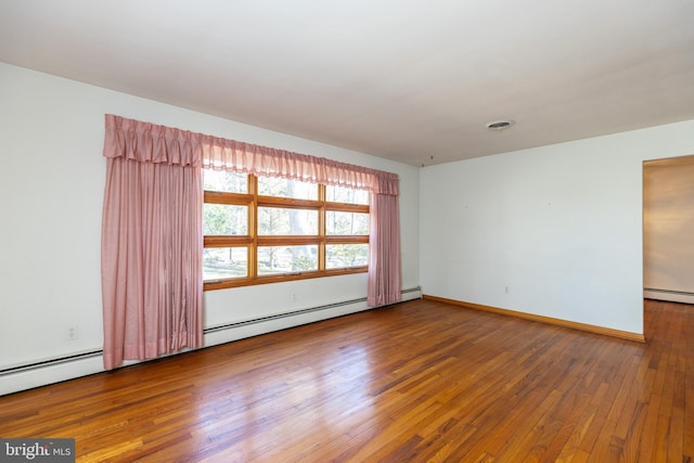 spare room with a baseboard radiator, wood-type flooring, visible vents, and baseboards