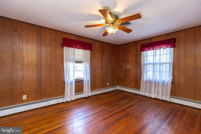 empty room featuring wood-type flooring, ceiling fan, and wooden walls