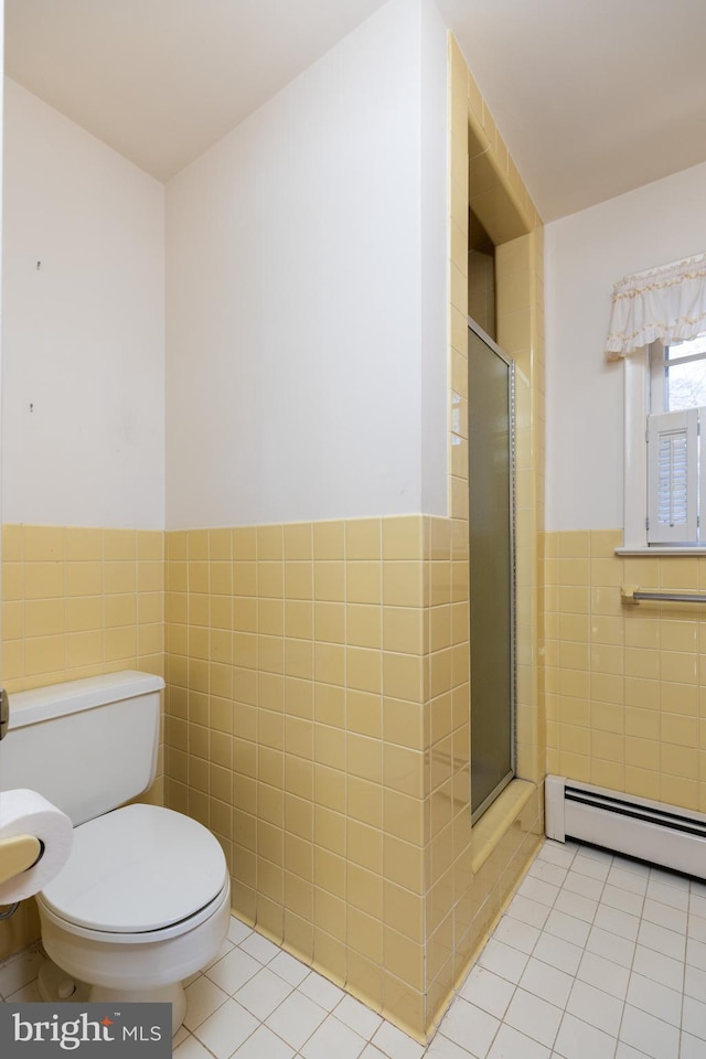 full bath with tile walls, toilet, a stall shower, wainscoting, and tile patterned flooring