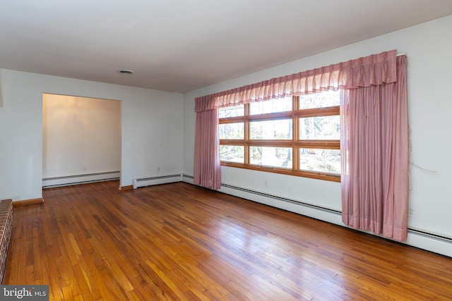 spare room featuring a baseboard heating unit, visible vents, and hardwood / wood-style flooring