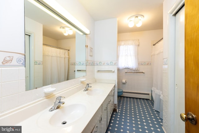 bathroom featuring a wainscoted wall, a baseboard radiator, tile walls, and a sink