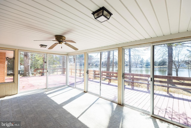 unfurnished sunroom featuring a water view and a ceiling fan