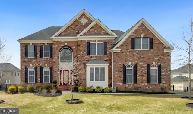 view of front of property with brick siding, fence, and a front lawn