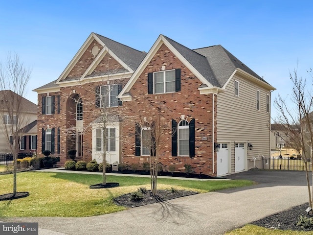 view of front of home with aphalt driveway, an attached garage, brick siding, fence, and a front yard