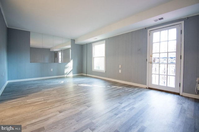 unfurnished living room with wood finished floors, visible vents, and baseboards