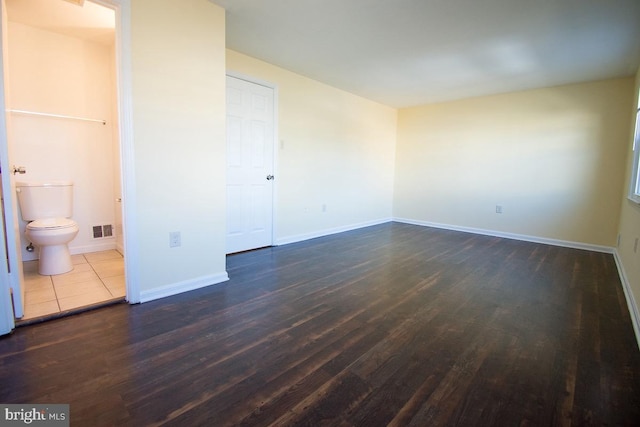 interior space featuring dark wood-style floors, visible vents, connected bathroom, and baseboards