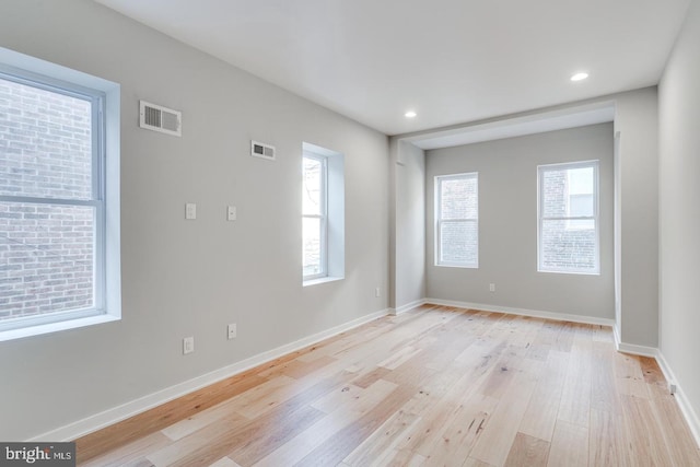 spare room featuring light wood-type flooring, baseboards, and visible vents