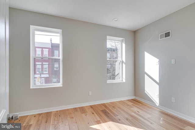 empty room featuring baseboards, visible vents, and wood finished floors