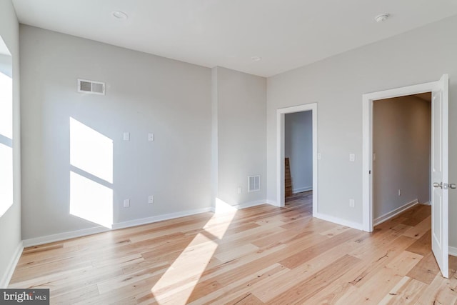 spare room featuring light wood-style floors, visible vents, and baseboards