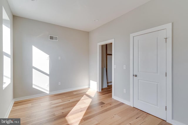 unfurnished bedroom with light wood-style flooring, visible vents, and baseboards