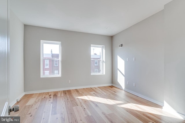 unfurnished room with visible vents, baseboards, a wealth of natural light, and wood finished floors