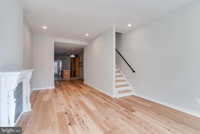 unfurnished living room with recessed lighting, a fireplace, baseboards, stairs, and light wood-style floors