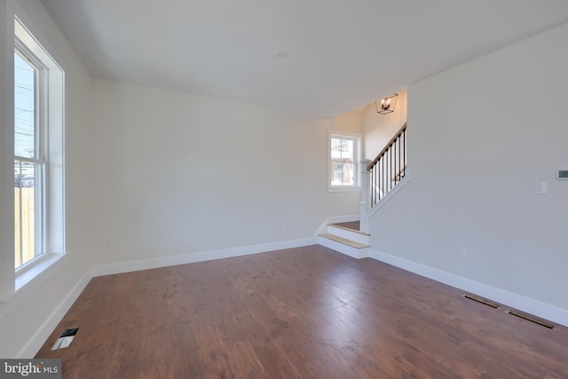 unfurnished living room with stairway, dark wood finished floors, visible vents, and baseboards