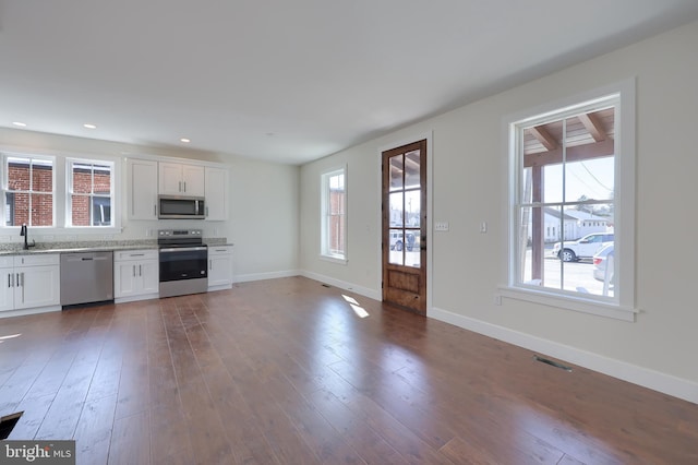 kitchen featuring stainless steel appliances, a sink, dark wood finished floors, and baseboards