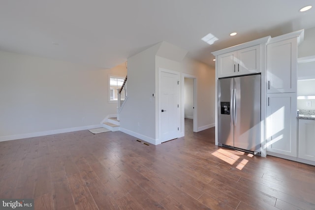 unfurnished living room featuring stairs, recessed lighting, hardwood / wood-style flooring, and baseboards