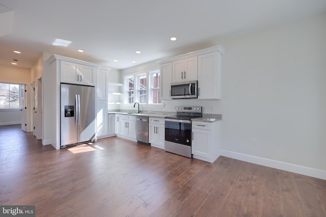 kitchen with dark wood-style floors, stainless steel appliances, a sink, and white cabinetry