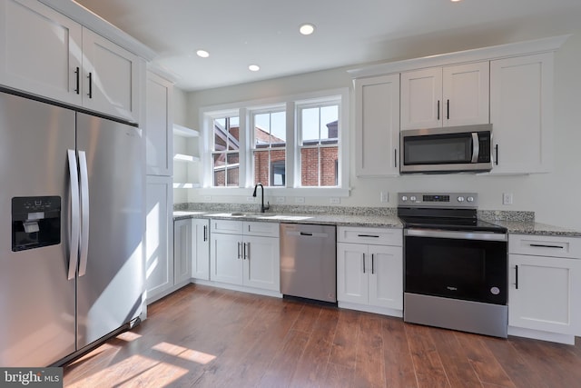 kitchen with stainless steel appliances, dark wood-style flooring, white cabinets, and a sink