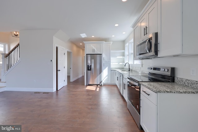 kitchen with white cabinets, dark wood-type flooring, stainless steel appliances, a sink, and recessed lighting