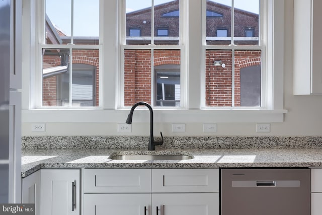 kitchen with dishwasher, a sink, white cabinetry, and light stone countertops