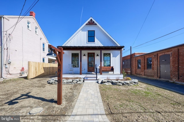 modern farmhouse with covered porch, fence, and board and batten siding