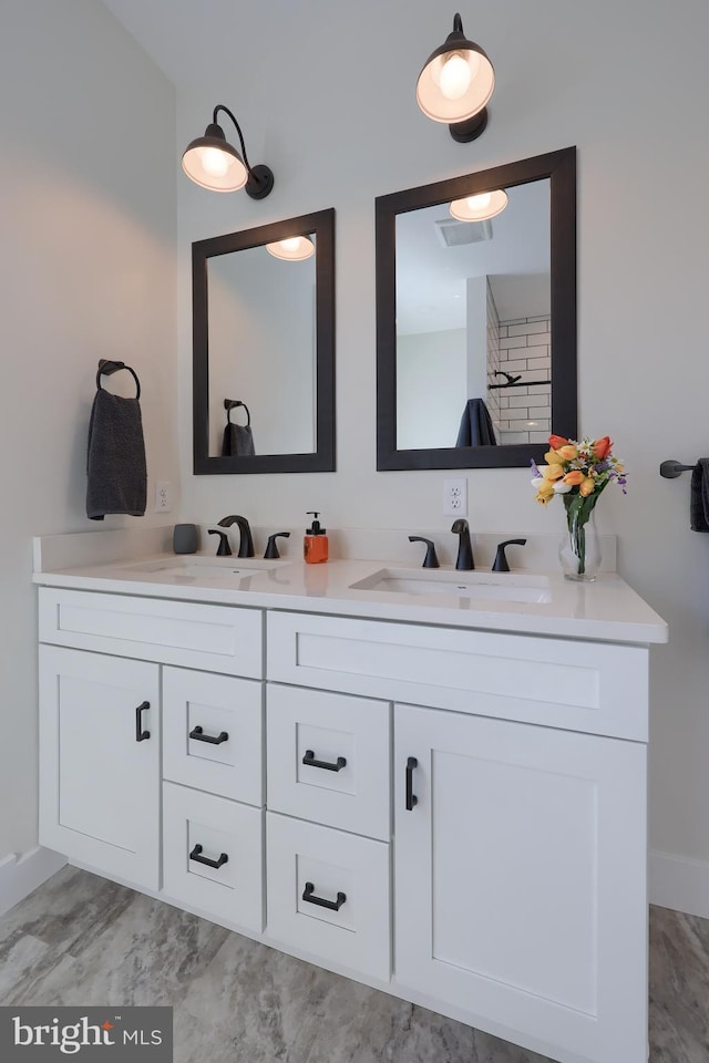 bathroom with double vanity, a sink, and visible vents