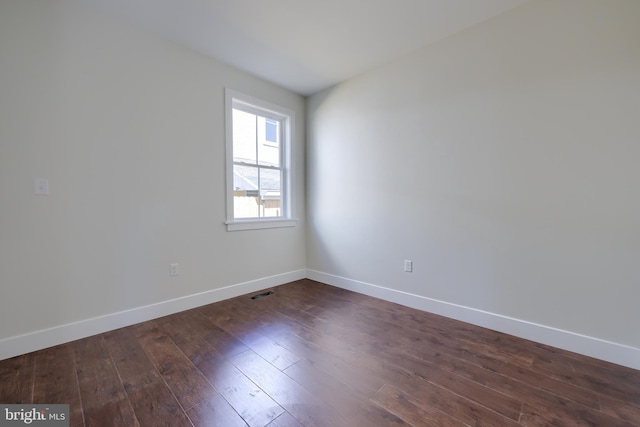 unfurnished room featuring visible vents, baseboards, and dark wood-type flooring