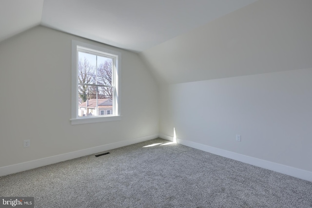 additional living space featuring vaulted ceiling, carpet, visible vents, and baseboards