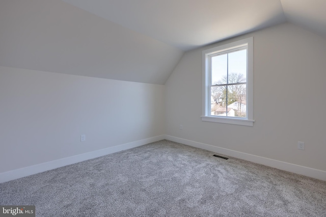 bonus room featuring lofted ceiling, carpet, visible vents, and baseboards