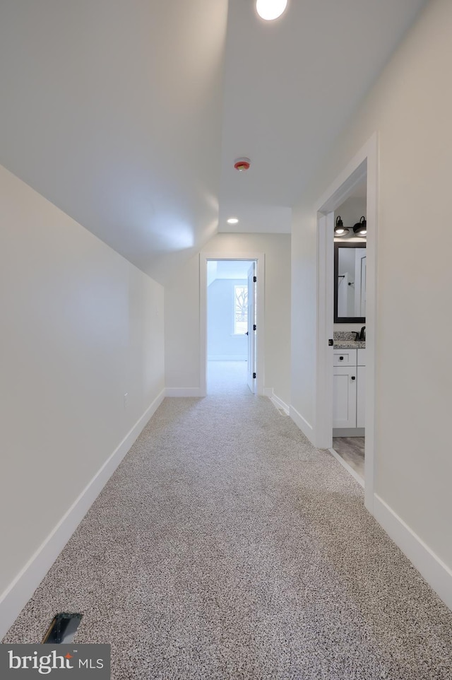 interior space featuring lofted ceiling, light carpet, and baseboards