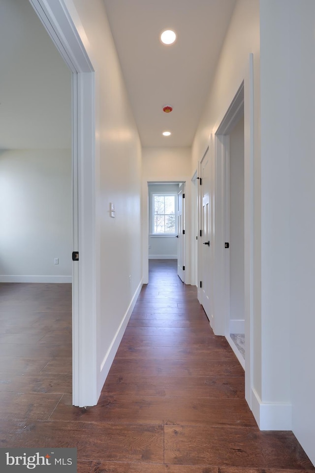 hall featuring baseboards, dark wood-type flooring, and recessed lighting