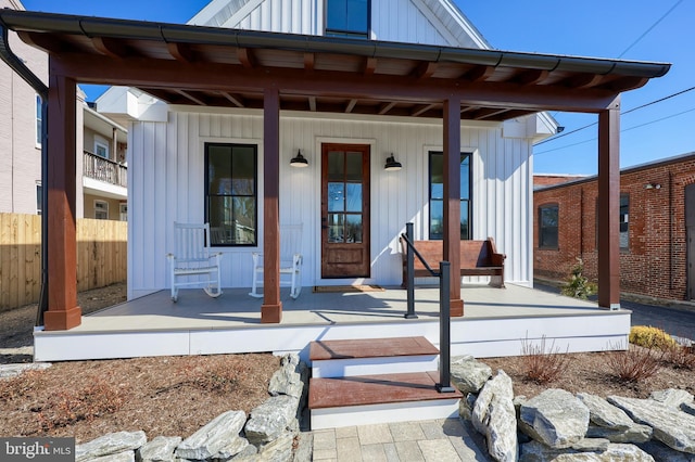 exterior space featuring covered porch, fence, and board and batten siding