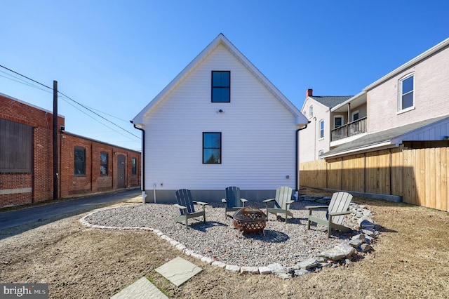 back of property featuring an outdoor fire pit and fence