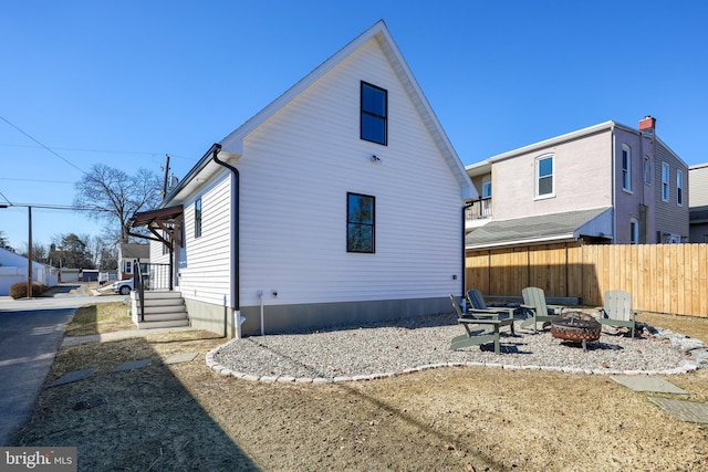 back of property featuring a fire pit and fence