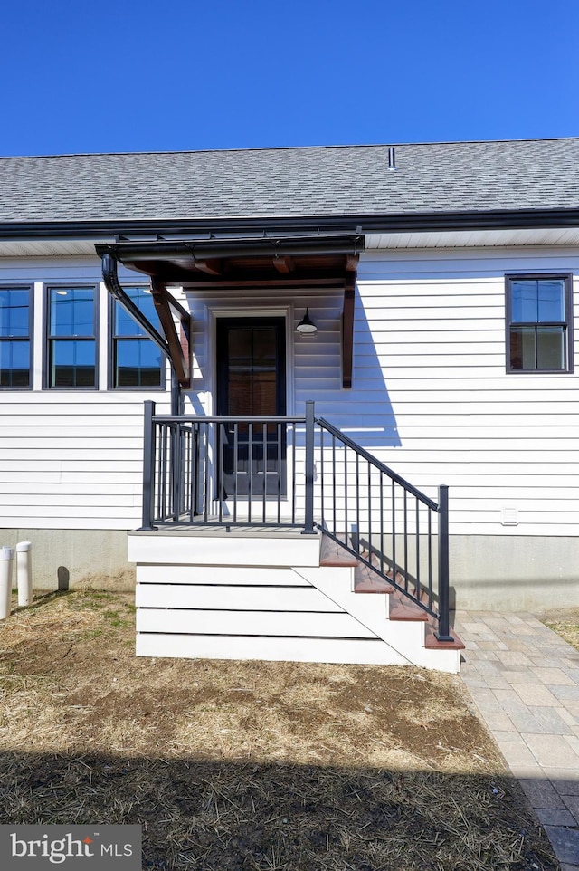 doorway to property with roof with shingles