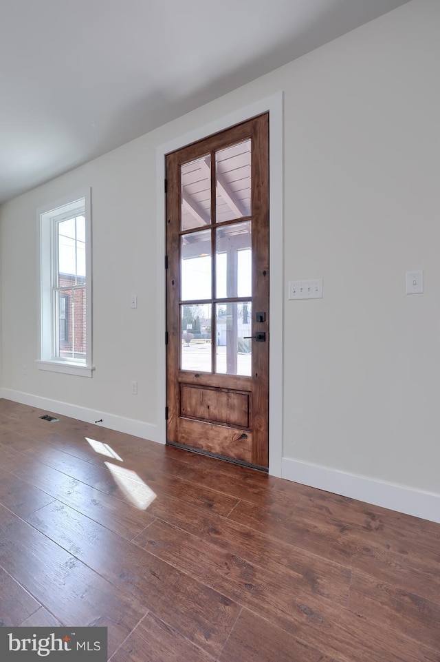 doorway with wood-type flooring, visible vents, and baseboards