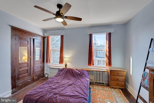 bedroom featuring radiator heating unit, multiple windows, and wood finished floors