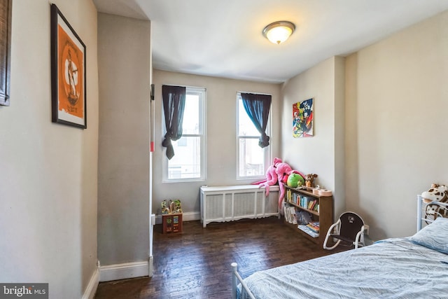 bedroom with radiator heating unit, wood finished floors, and baseboards