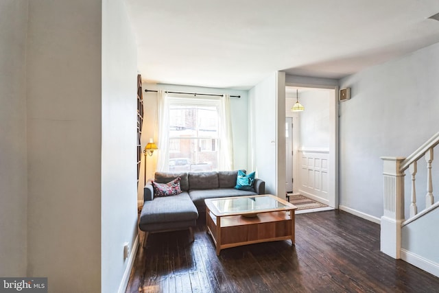 living room featuring baseboards, stairway, and dark wood-type flooring