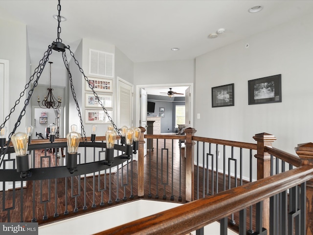 hallway with visible vents, an upstairs landing, and wood finished floors