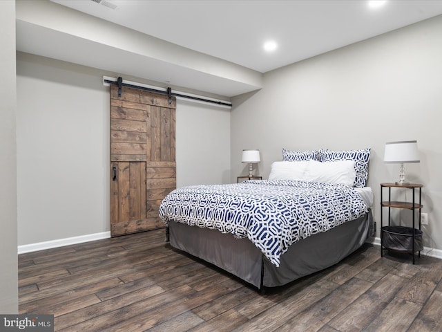 bedroom with a barn door, wood finished floors, and baseboards