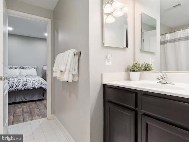 ensuite bathroom with visible vents, ensuite bathroom, vanity, baseboards, and tile patterned floors