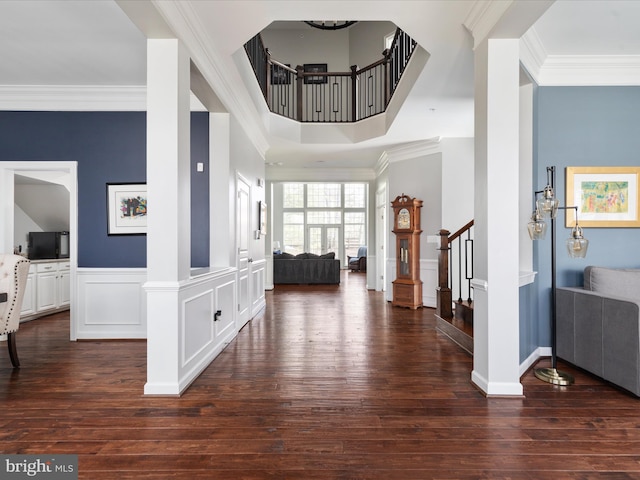 entryway with dark wood-style floors, stairway, crown molding, and a wainscoted wall