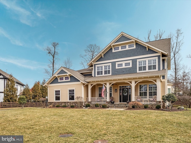 shingle-style home with a porch, roof with shingles, a front yard, and fence