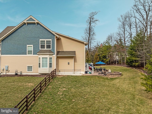 back of property with a patio, an outdoor fire pit, a lawn, and fence