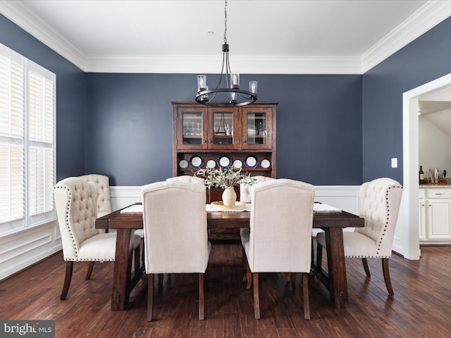 dining room featuring crown molding, wainscoting, a notable chandelier, and wood finished floors