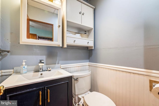 bathroom with wainscoting, vanity, and toilet